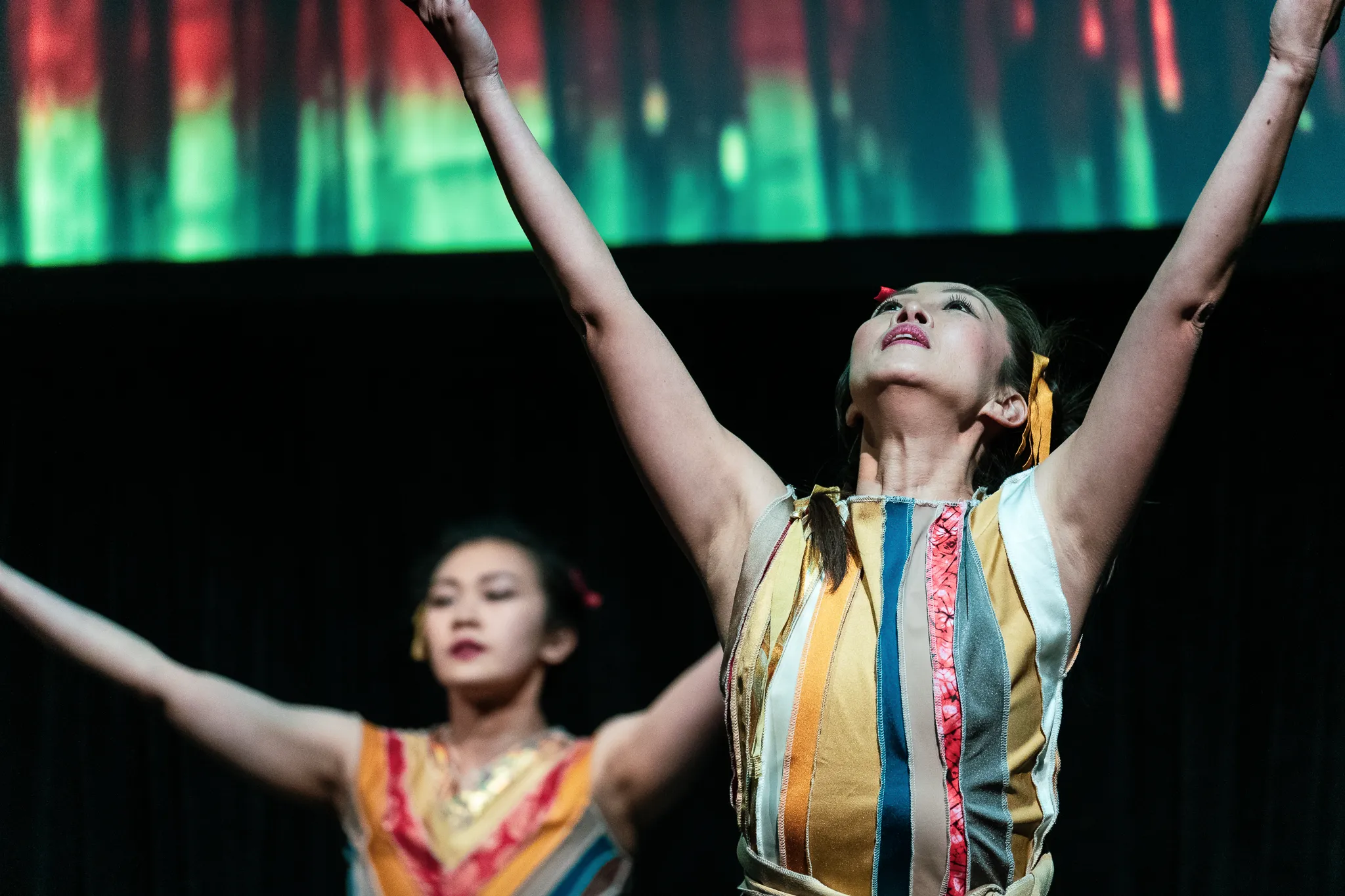 A dancer looking upward with both arms raised