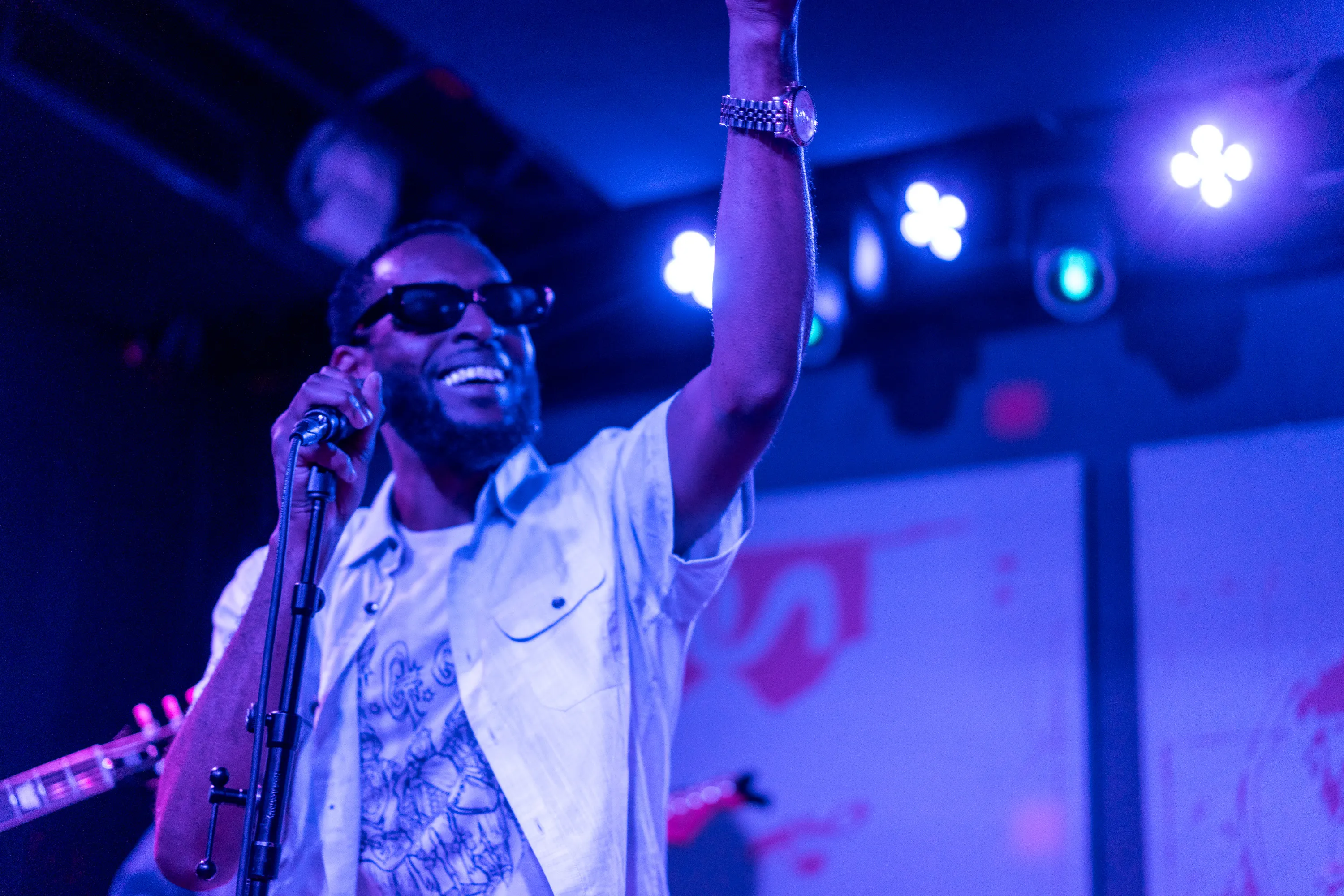 A smiling vocalist raising one arm toward the crowd