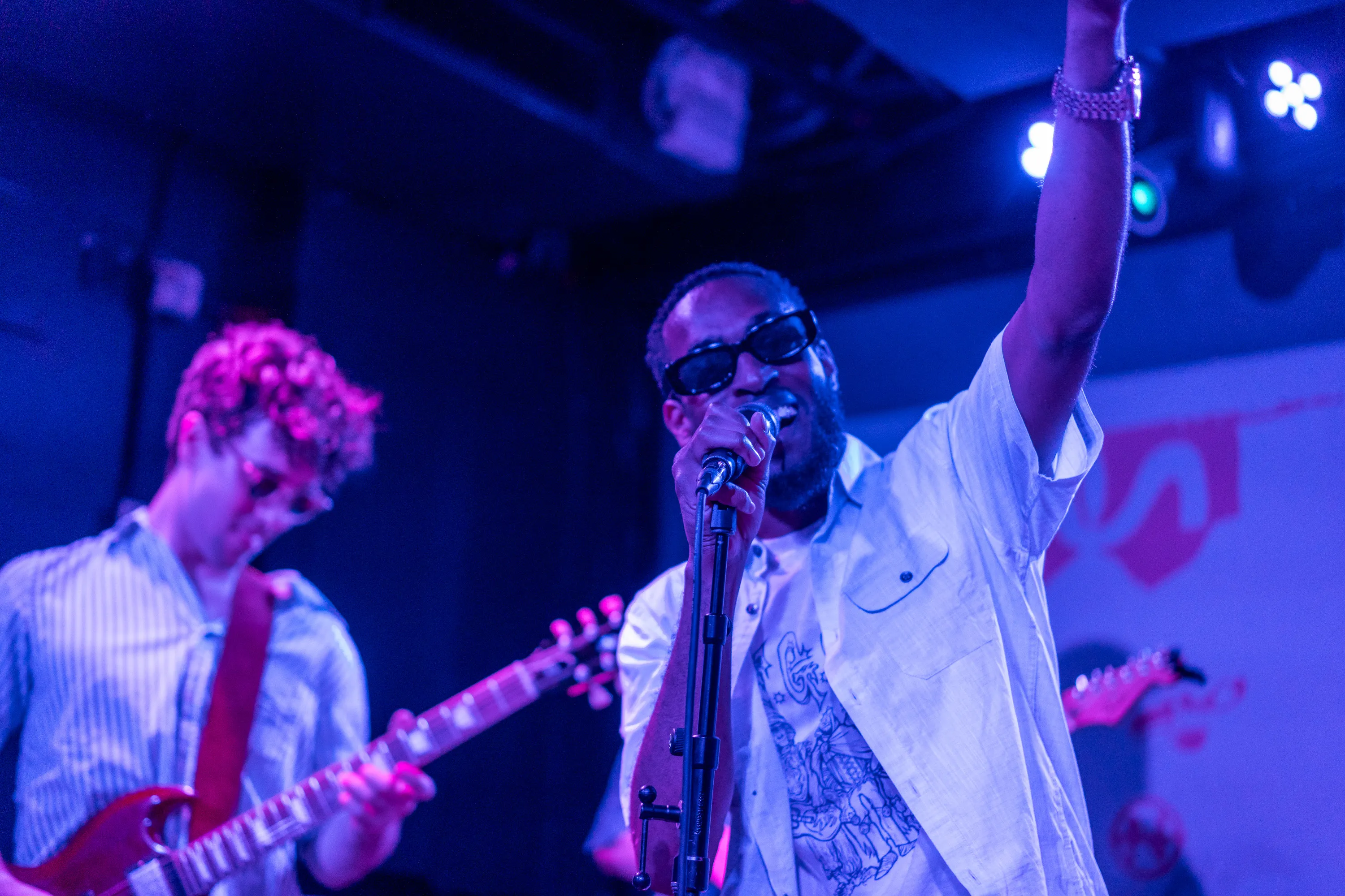 A vocalist singing with one arm raised beside a guitarist